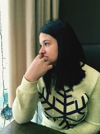 Portrait of beautiful woman sitting on table at home