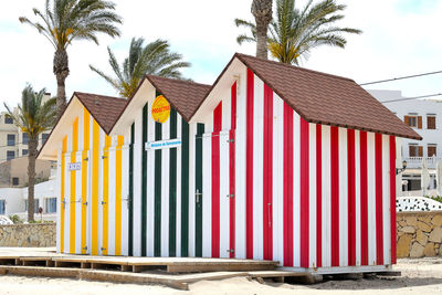 Multi colored houses on beach by building against sky