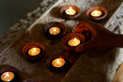 Candles light background with young woman hand taking one candle. 