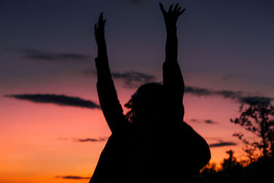 Silhouette woman against orange sky