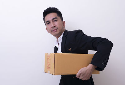 Portrait of man holding camera against white background