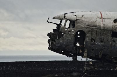 Abandoned airplane on sea shore against sky