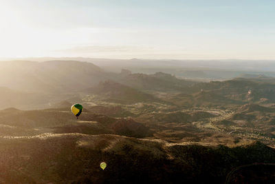 Hot air balloons over landscape against sky