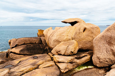 Rocks on shore by sea against sky