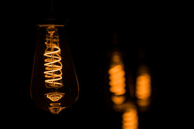 Close-up of illuminated light bulb against black background