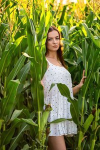 Portrait of young woman standing amidst plants