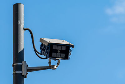 Low angle view of telephone pole against clear blue sky