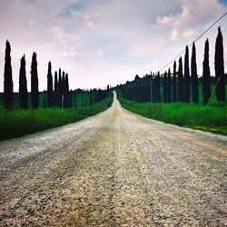 Empty road amidst field against sky