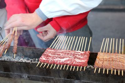 Chef cooks meat of lamb called arrosticini in italian language.