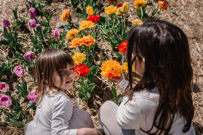 Two girls in white sitting in the tulip field watching flowers