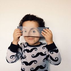 Cute boy holding paper with eyes painted on it