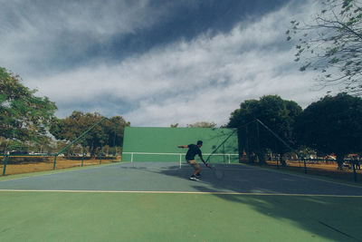 People playing basketball court against sky