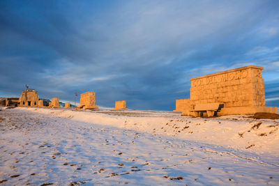 Buildings on snow covered land against sky