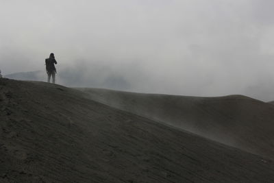 Man on arid landscape against sky