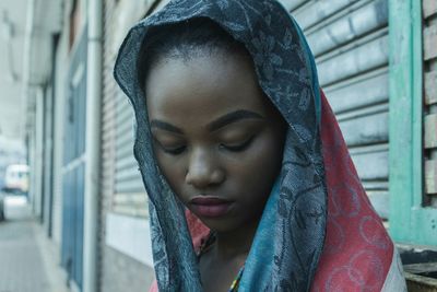 Young woman wearing scarf looking down against wall