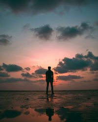 Silhouette man standing on beach against sky during sunset