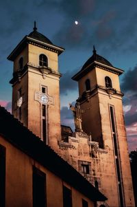 Low angle view of clock tower amidst buildings against sky