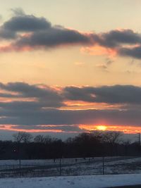 Scenic view of snow covered landscape against sky at sunset