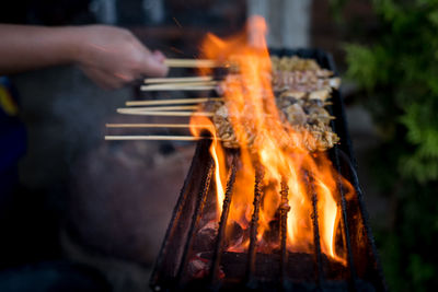 Close-up of person preparing food on barbecue grill