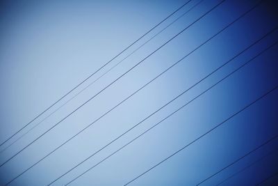 Low angle view of power lines against blue sky