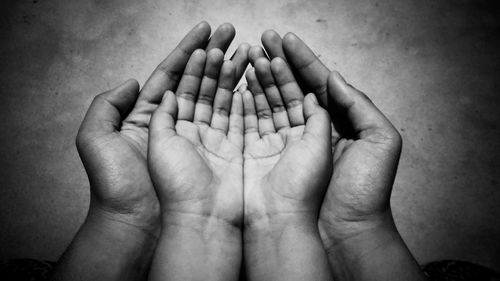 Cropped hands of parent and child against wall