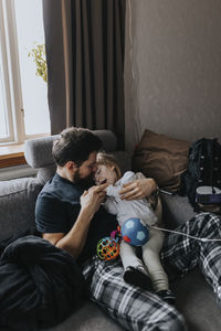 Father hugging disabled child on sofa