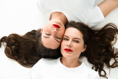 Two beautiful women twin sisters close-up face portrait, laying on floor