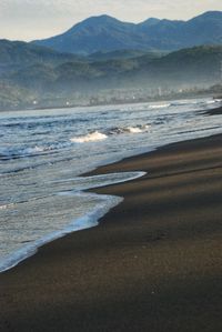 Scenic view of beach and mountains against sky