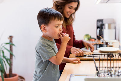 Mother preparing food by son in kitchen