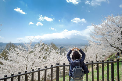 Man standing by railing against sky