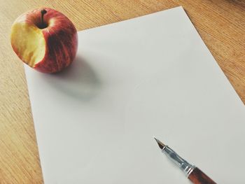 Close-up of apple and pen on paper