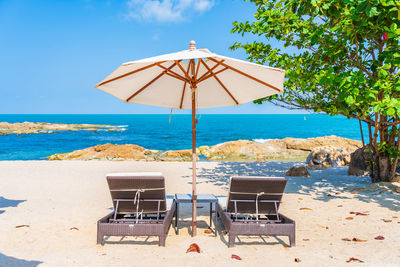 Deck chairs on beach against sky
