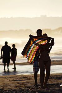 Two men on multi colored umbrella against sky