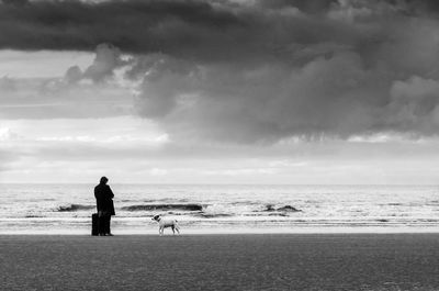 Woman and dog on beach against sky