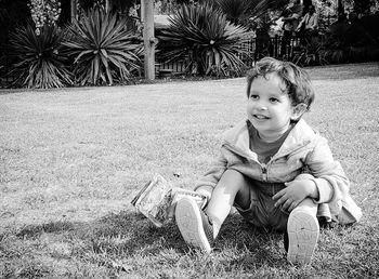 Boy looking away while sitting on field 