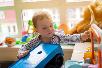 Toddler boy plays with car toys in the children's room. educational toys for young children.