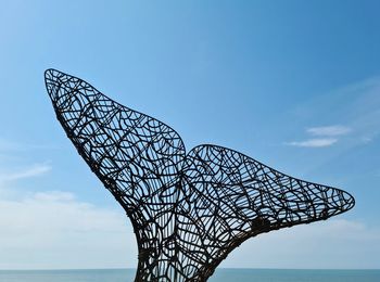 Metal whale fin against crear sky