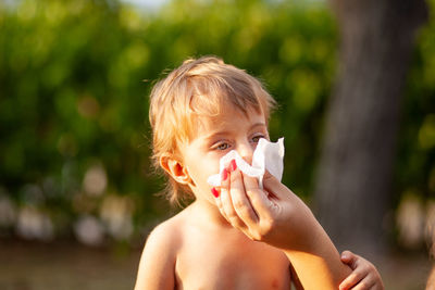 Cropped hand of mother wiping mouth of son 