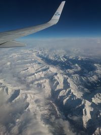 Aerial view of airplane wing over landscape against sky