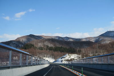 Road leading towards snowcapped mountains against sky