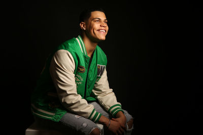 Portrait of young man standing against black background