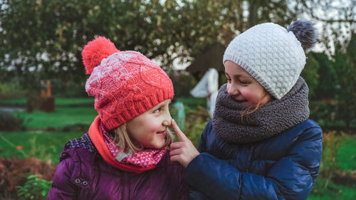 Close-up of sisters wearing warm clothing at park during winter