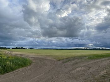 Road amidst field against sky