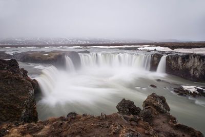 Scenic view of waterfall against sky