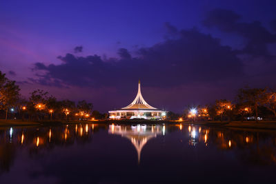 Illuminated bridge over river against sky at night