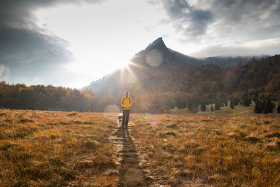 Full length of woman standing with dog on field