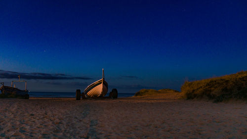 Lifeguard hut on beach against clear blue sky at night