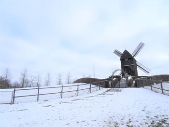 Windmill on snow covered land against sky