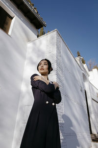 Beautiful woman standing with arms crossed in front of white building