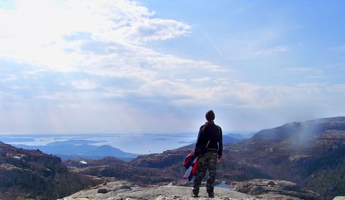 Rear view of man standing on mountain against sky